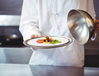 Chef raising a bell of a dish in commercial kitchen